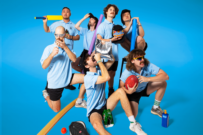 Australian band Playlunch members wearing light blue shirts posing playfully with pool noodles and sports gear against a blue background.